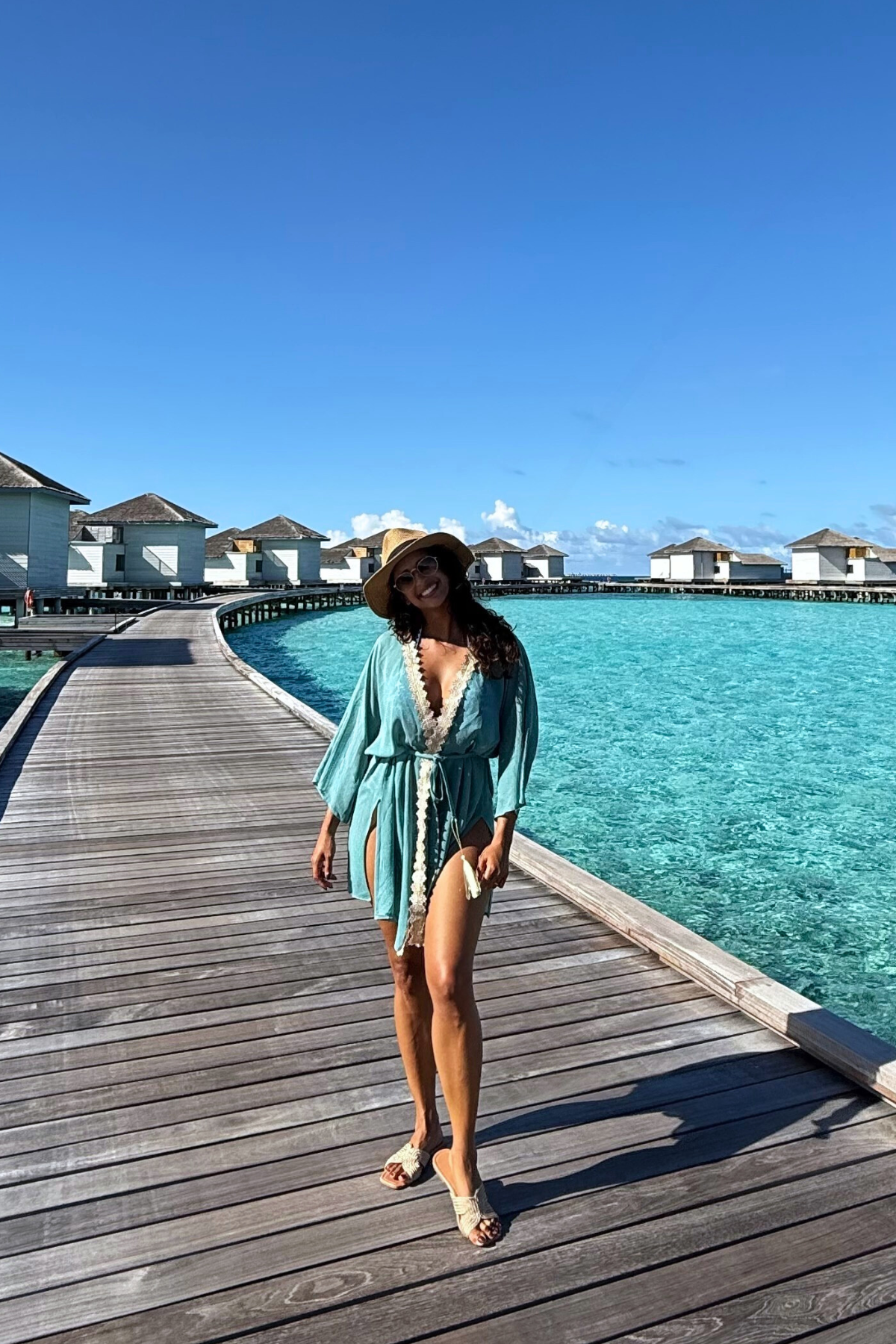 Frau trägt modernen türkisen Kaftan als Sommerkleid am Strand im Urlaub. Leichter Resort Wear Kaftan mit goldenen Details von Sefa Kaftans.